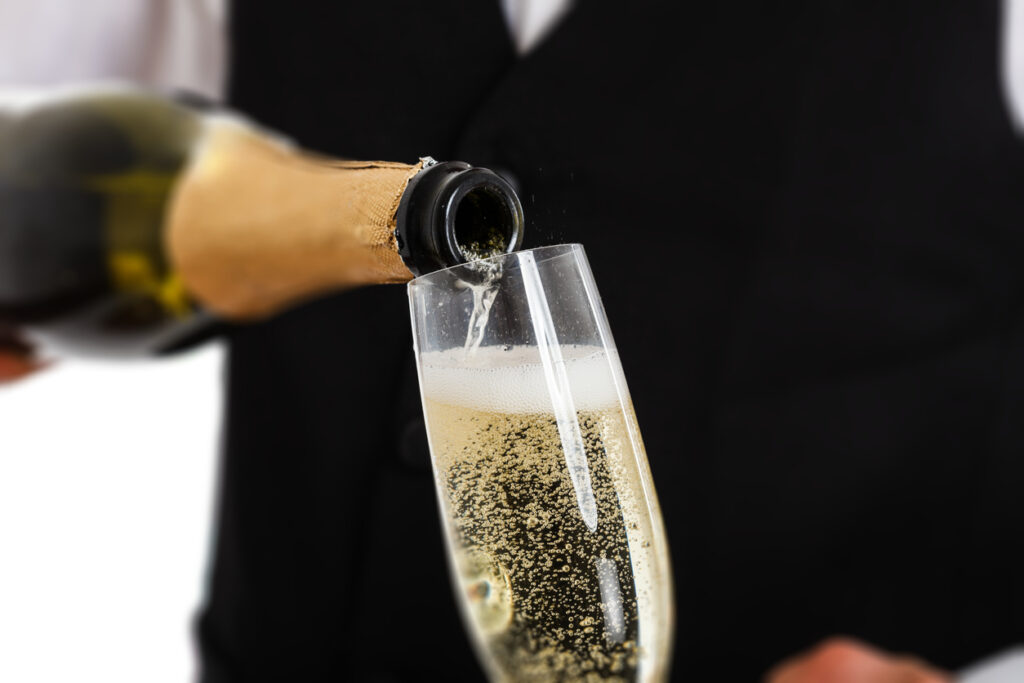 Portrait of a waiter pouring champagne into a flute