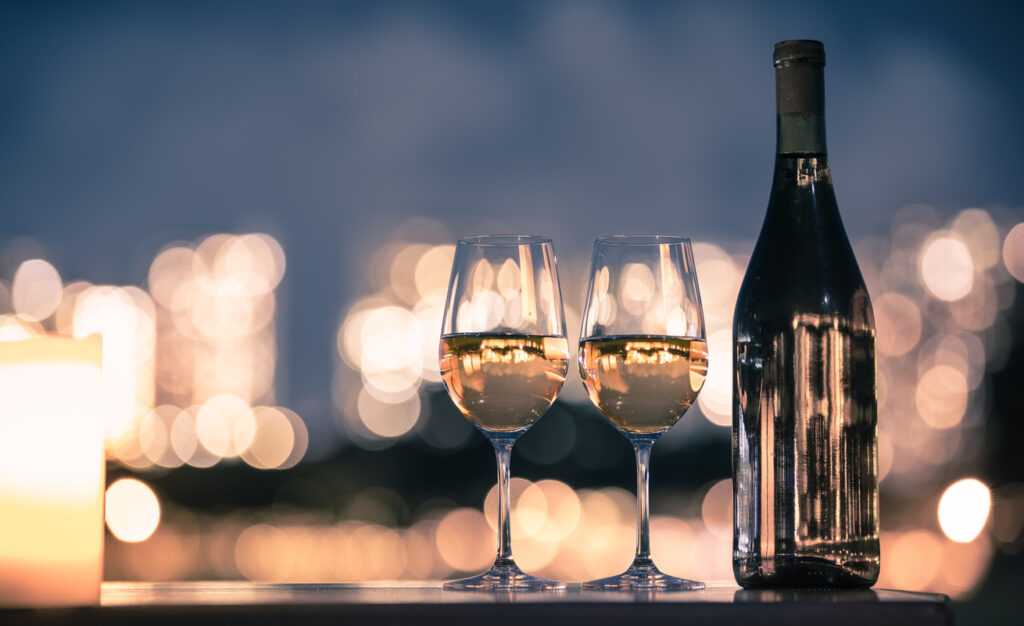 Pair of wine glasses on table against a romantic city light background.
