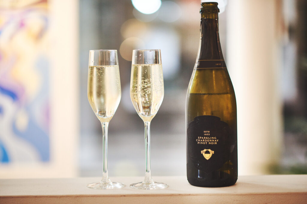 Still life shot of a bottle of champagne along side two champagne flutes indoors