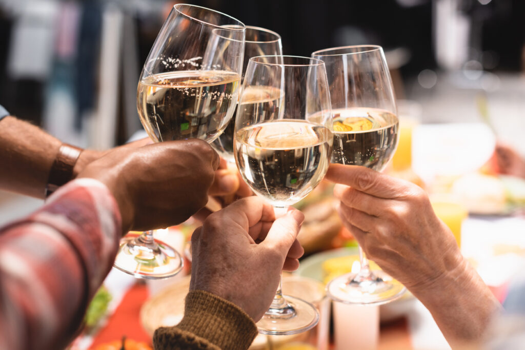 cropped view of multicultural relatives clinking wine glasses during thanksgiving dinner