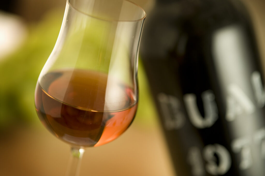 "Breuberg, Germany - March 8, 2012: Close-up shot of a glass of Madeira Wine from 1977. Selective focus. Madeira is a produced on the Madeira Islands. The name Madeira is trademarked for only the the wines produced on the Portuguese Island. There are different styles some can be used as an aperitif while others are usally used with the desert. This Madeira wine was made from the Bual grape in 1977. Although the wine is very dark it is made from a white grape."