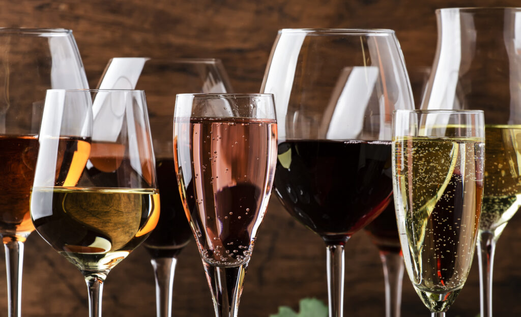 Wine tasting. Red, white, rose and champagne - still and sparkling wines sin glasses on vintage wooden table background