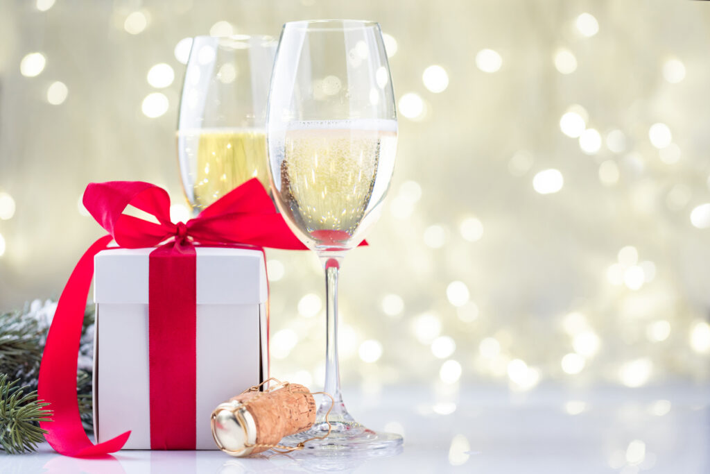 Champagne glasses and gift box in front of Christmas lights bokeh