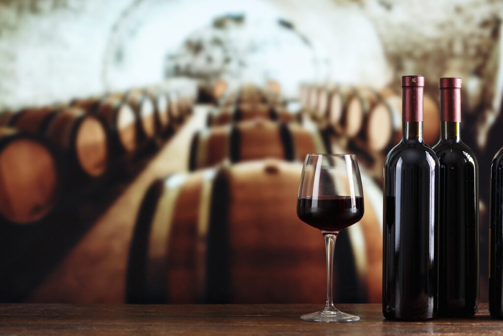 A bottle of wine and glasses with wine on a barrel in a wine cellar. Making and tasting wine