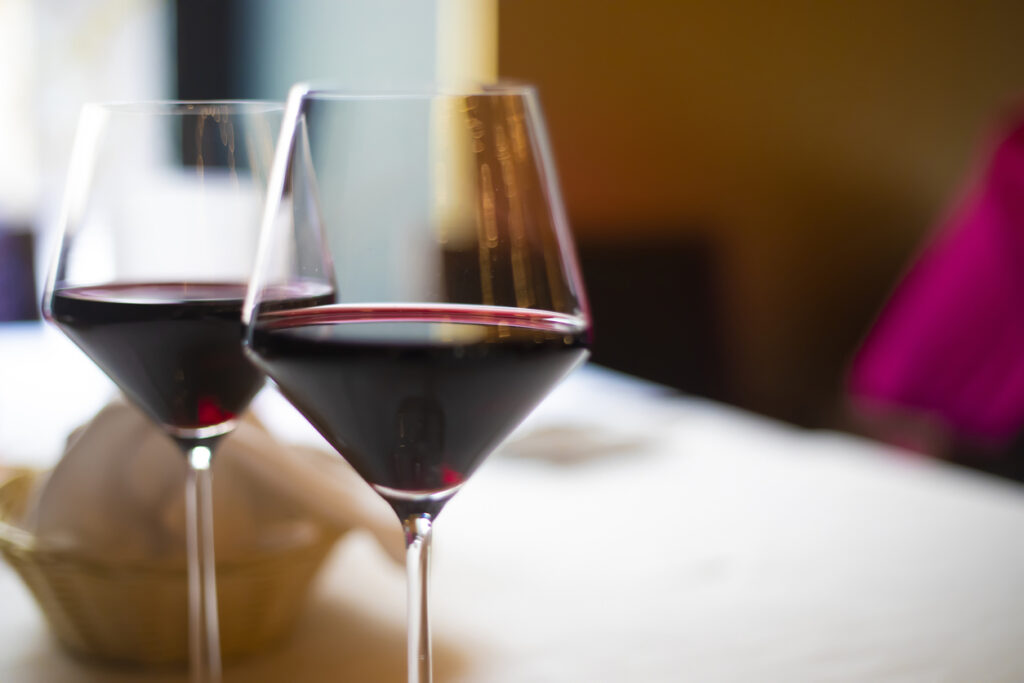 Two glasses of red wine standing on a table in a restaurant