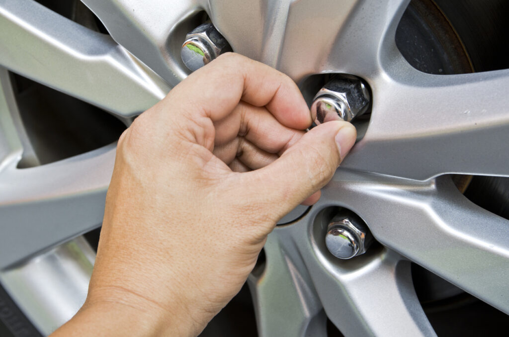 Replacing lug nuts by hand while changing tires on a vehicle.