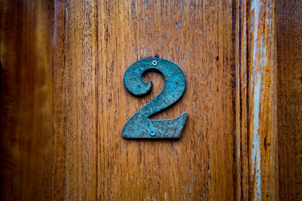 Bronze house number two (2)  on a wooden door