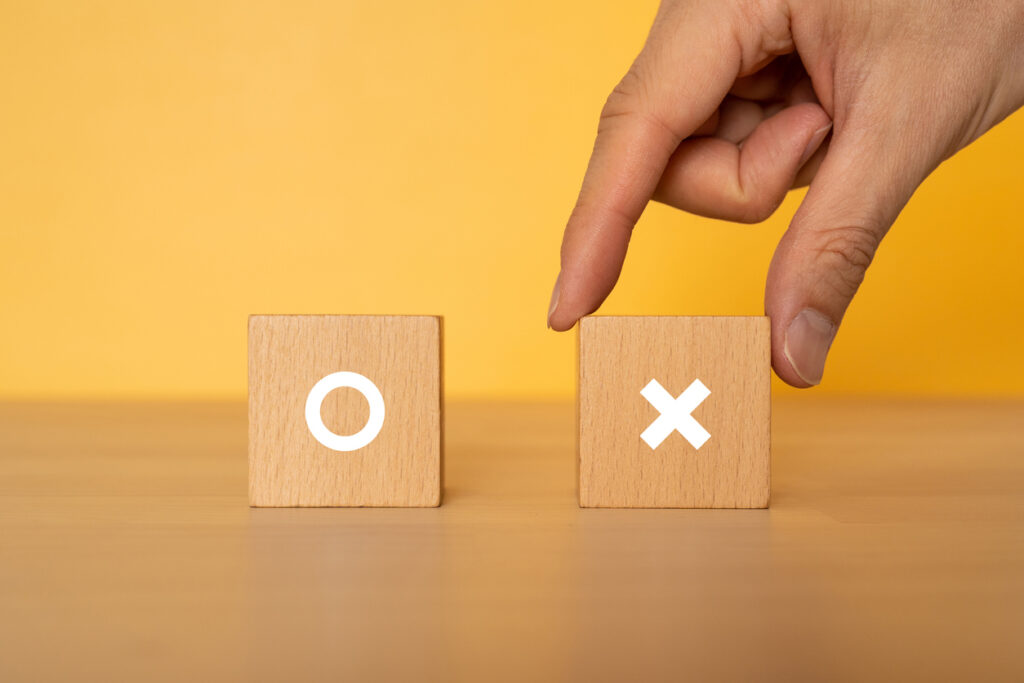 Wooden blocks with "○×" text of concept and a hand.