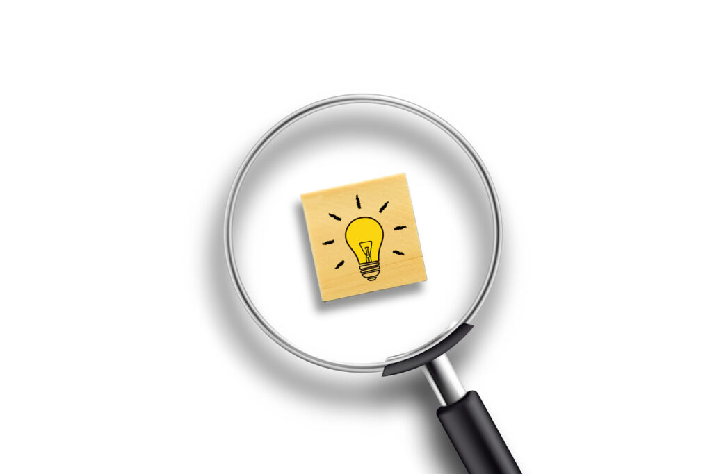 Creative idea concept, magnifying glass and light bulb icon on wooden block with white background