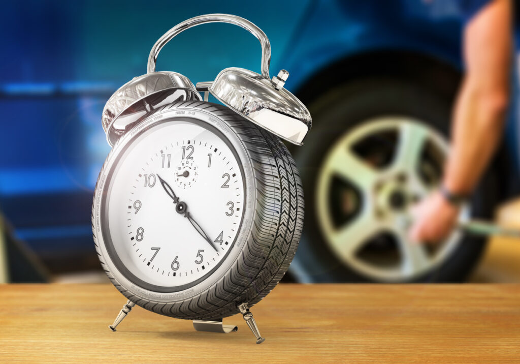 Alarm clock in form of car wheel on a blurred background. 3d illustration