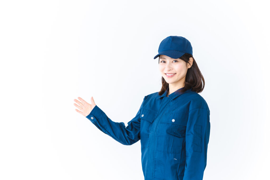 Young woman in work clothes smiling and pointing