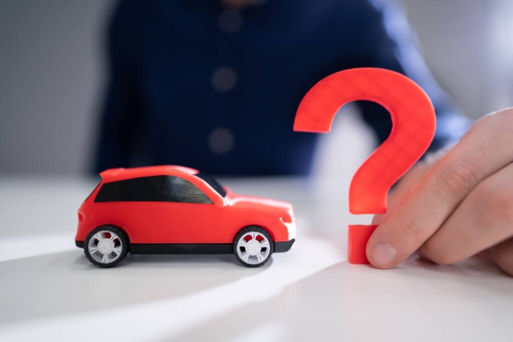 Person Hand Holding Question Mark Next To Car Model